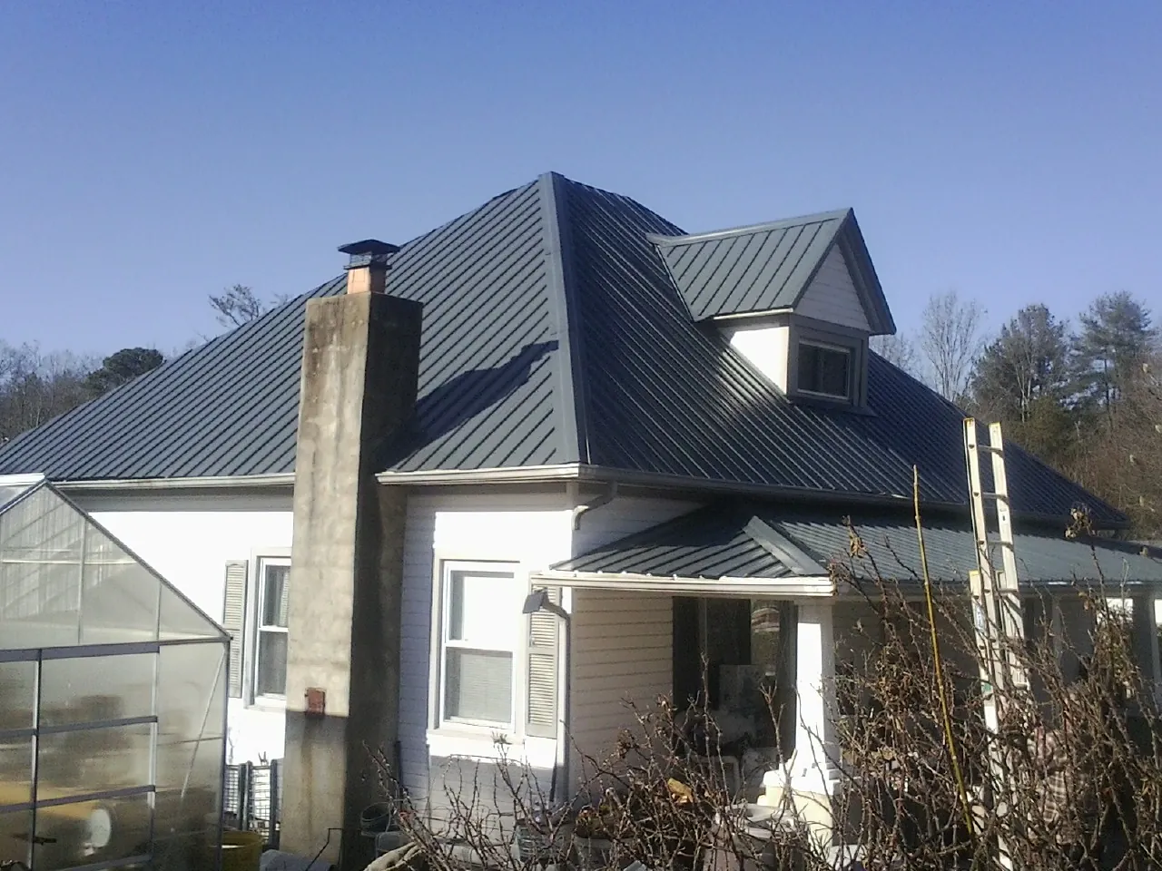Dark blue standing seam metal roof on a white farmhouse with dormer — Slate & Tile Roof Repair by Roofing Brothers in Reddell
