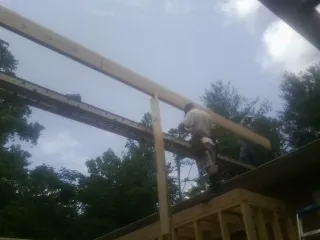 Carpenter setting a ridge beam over a new addition frame — Ice Dam Removal by Roofing Brothers in Reddell