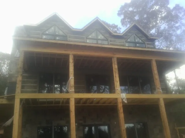 Dormers and porch framing on a large log home under construction — Roof Coating work by our crew in Reddell