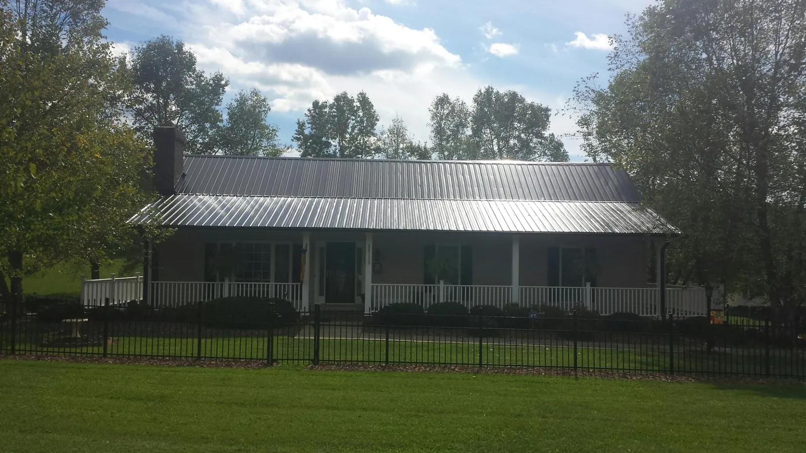 Gray metal roof on a brick ranch with a full width front porch — Gutter Guard Installation work by our crew in Reddell