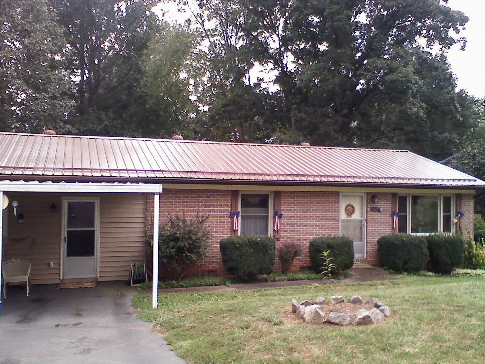 Bronze metal roof and carport on a brick ranch home — Roof Repair work by our crew in Reddell